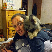 Einstein joined the competition — help win amazing prizes! man, dog, bed, pillow, furniture, room, indoor, casual, pet, animal, human, face, expression, wooden_dresser, sign, curious, playful, coat, clothing, relaxing