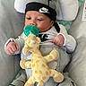 Jaylen is registered to the contest to win money with this photo: baby, infant, pacifier, plush_toy, giraffe, nike, hat, clothing, onesie, seat, cushion, indoor, cute, child, person, baby_clothes, resting, soft_toy, gray, white