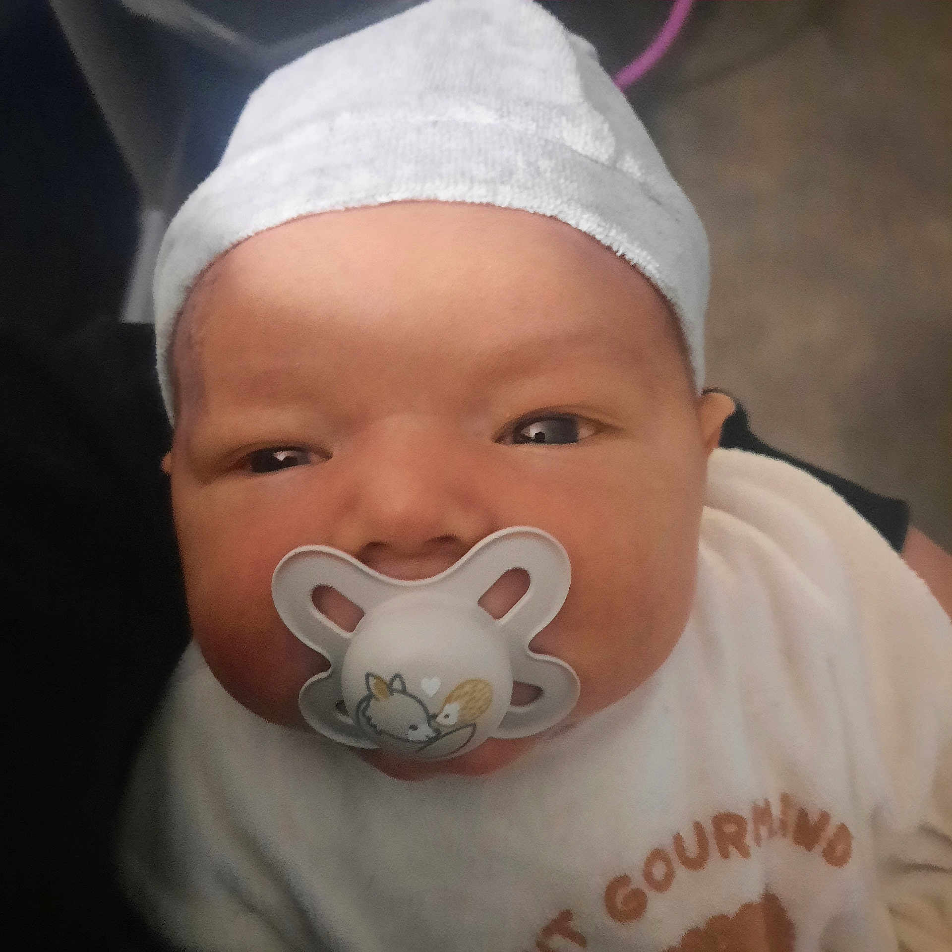 Maëlio participe au concours pour gagner de l'argent avec cette photo : baby, infant, pacifier, white_hat, close_up, face, child, sleepy, cute, adorable, newborn, person, clothing, portrait, indoor, soft_lighting, young, headwear, baby_girl, baby_boy