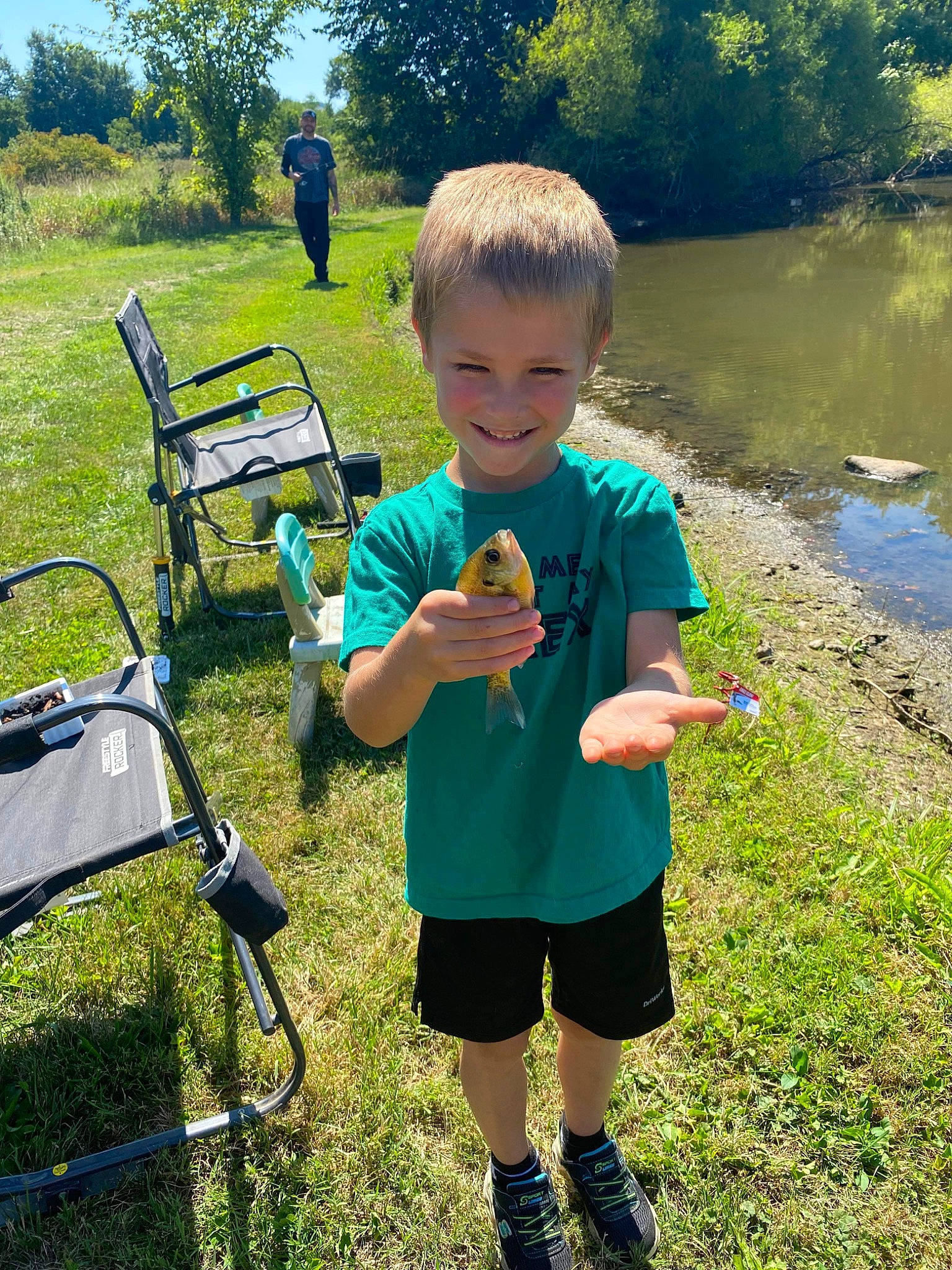 Logan is registered to the contest to win money with this photo: child, fun, grass, grass_family, grassland, happy, joy, landscape, lawn, leisure, outdoor_furniture, people_in_nature, person, plant, recreation, shorts, smile, summer, t_shirt, toddler