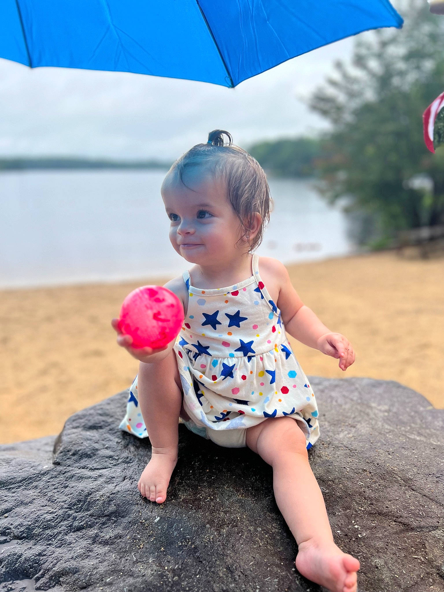 Ruari is registered to the contest to win money with this photo: azure, baby_toddler_clothing, beach, blue, child, dress, happy, head, leisure, morning, people_in_nature, people_on_beach, person, photograph, red, shade, tints_and_shades, toddler, tree, umbrella