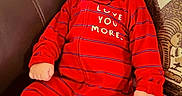 Yaman is registered to the contest to win money with this photo: baby, bear_socks, brown_leather, child, comfortable, couch, cute, footed_pajamas, homedecor, indoor, infant, love_message, pillow, portrait, red_onesie, relaxed, seated, soft_lighting, striped_clothing, young_child