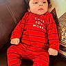 baby, infant, red_onesie, striped_clothing, couch, brown_leather, pillow, cute, child, footed_pajamas, bear_socks, indoor, comfortable, relaxed, portrait, young_child, soft_lighting, love_message, seated, homedecor