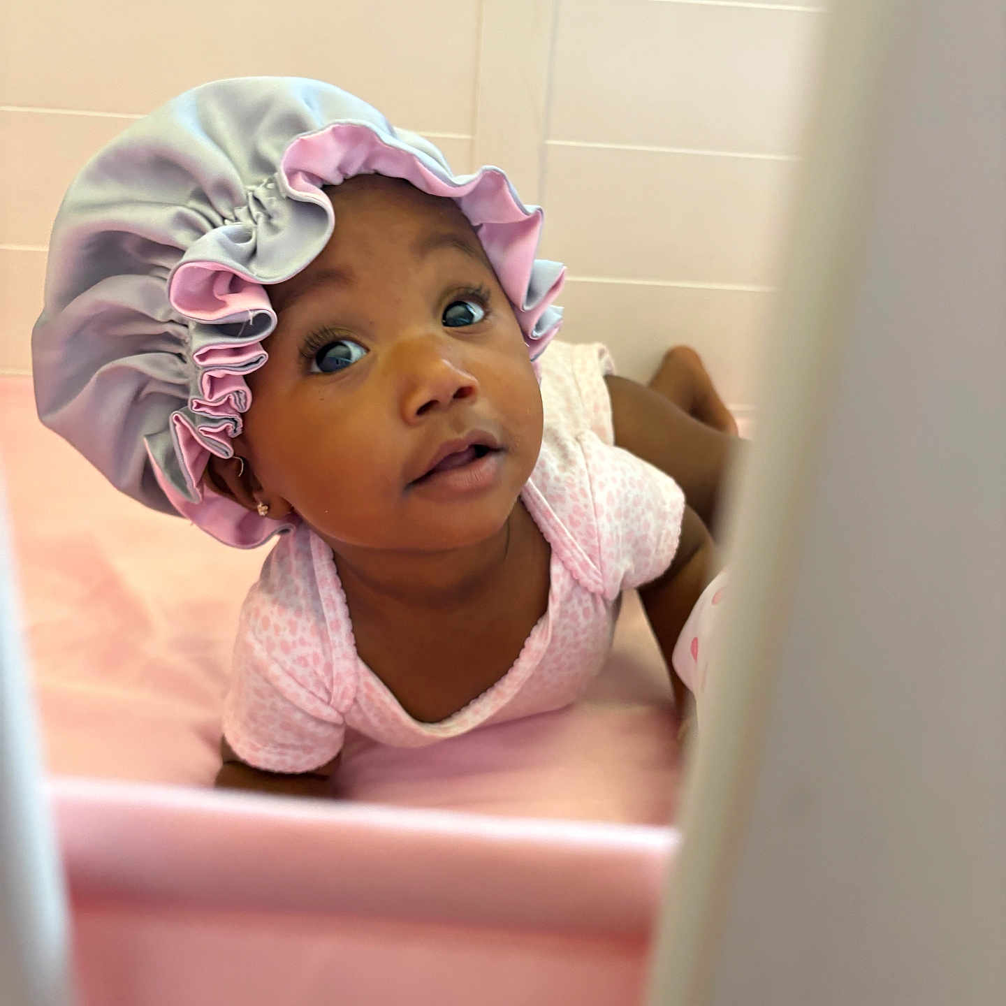 Aliyanah is registered to the contest to win money with this photo: adorable, baby, baby_clothes, bonnet, child, curious, cute, expression, face, headwear, indoor, infant, lying_down, onesie, pink, portrait, skin, soft, tummy_time, young_child