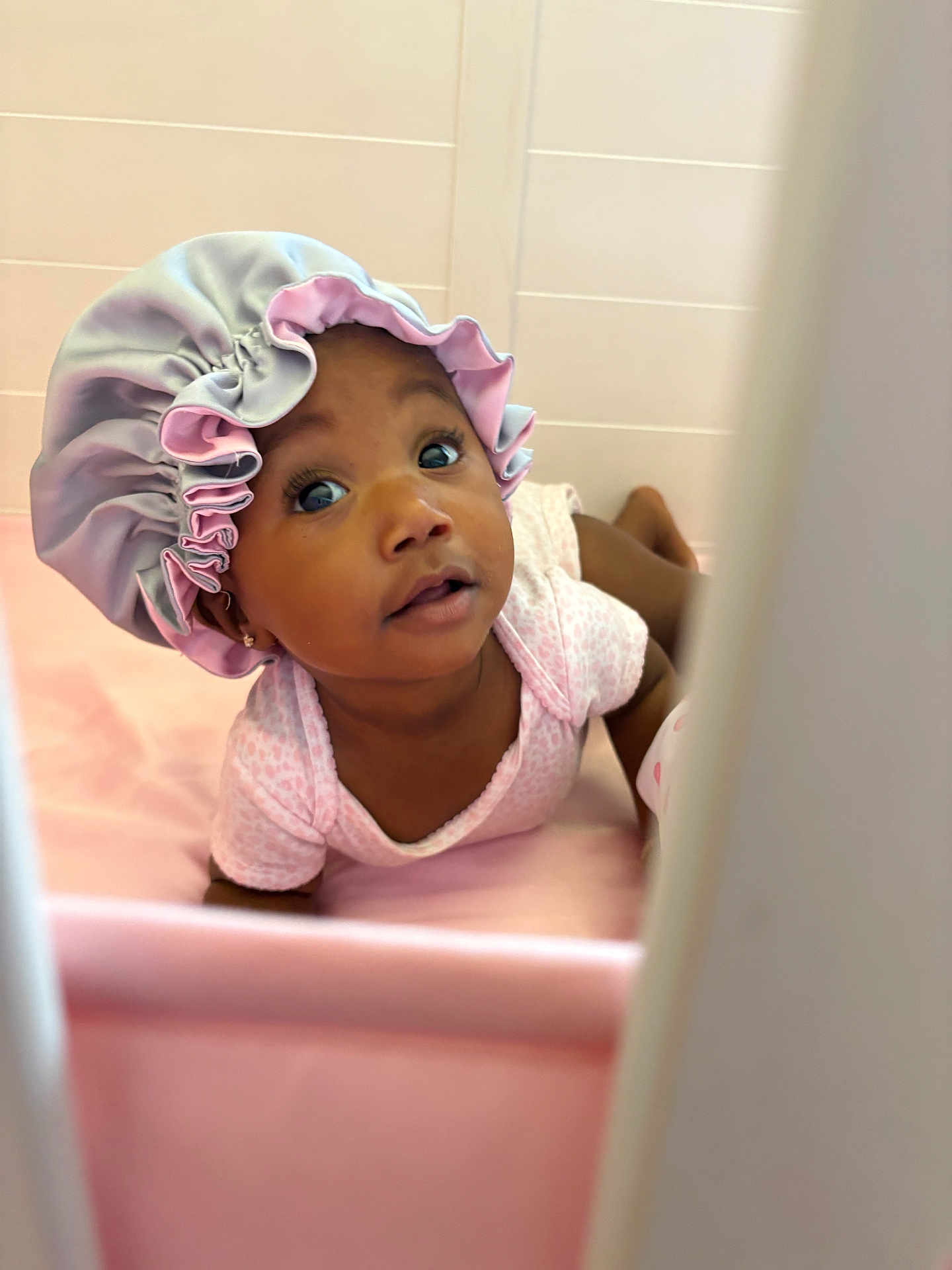 Aliyanah is registered to the contest to win money with this photo: baby, infant, child, pink, bonnet, cute, tummy_time, onesie, soft, indoor, curious, face, portrait, baby_clothes, headwear, skin, adorable, lying_down, expression, young_child