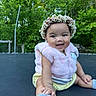 baby, casual_clothing, child, cute, flower_crown, fun, greenery, happy, infant, nature, outdoor, pink_vest, playful, portrait, sitting, smile, sunlight, trampoline, trees, young_child