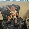 Michael is registered to the contest to win money with this photo: toddler, child, chair, starfish_pattern, clothing, indoor, window, urban_view, casual, sitting, cute, person, shorts, tank_top, footwear, relaxed, home, curtain, furniture, portrait