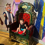 Michael joined the competition — help win amazing prizes! child, toddler, throne, chair, smile, indoor, floor, cartoon_characters, wall_art, colorful, royal, decorative, portrait, happy, shorts, tank_top, footwear, playful, light, shadow