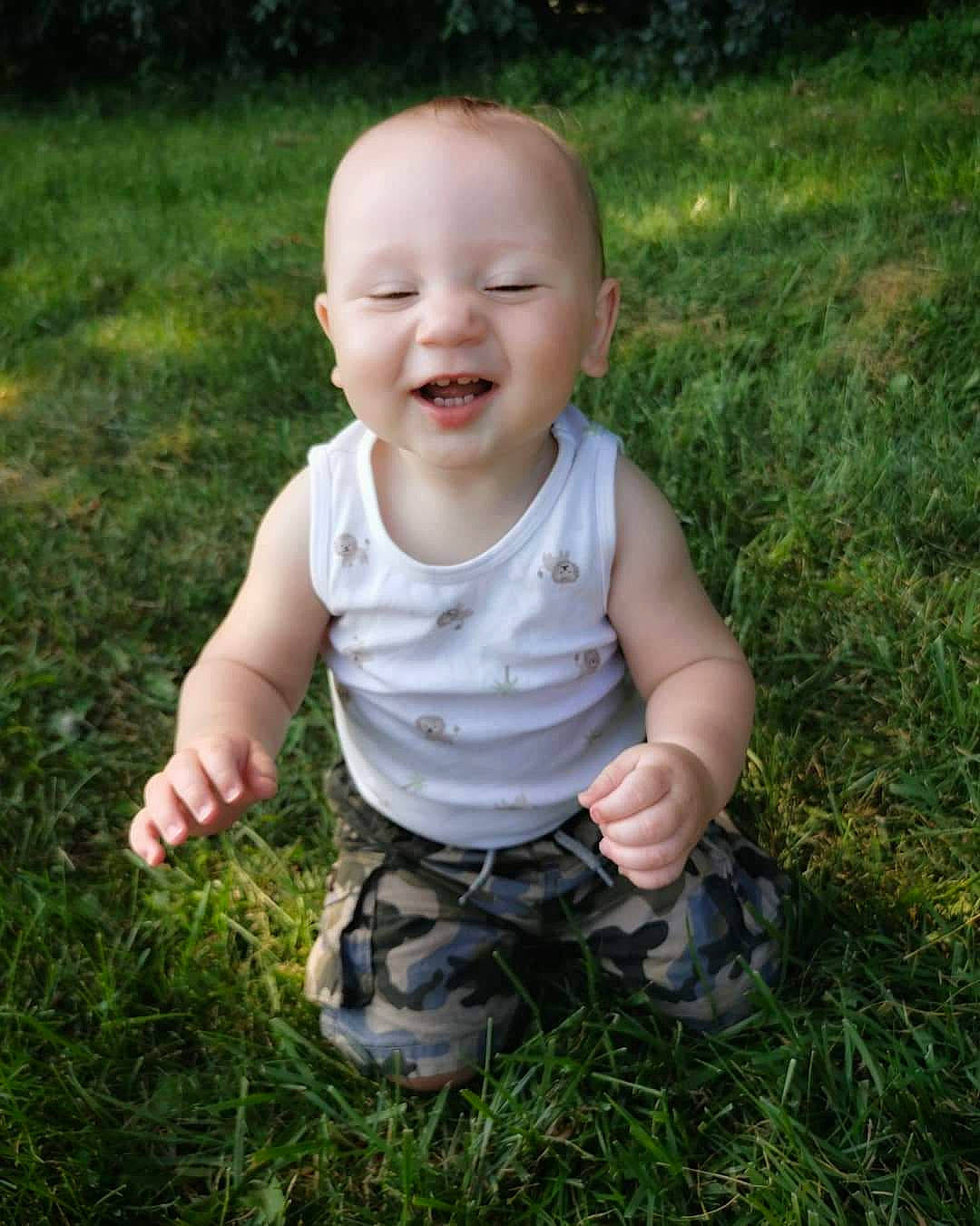 Marvin is registered to the contest to win money with this photo: baby, baby_toddler_clothing, cheek, child, facial_expression, finger, grass, grass_family, happy, head, lawn, meadow, nose, person, photograph, photography, plant, sitting, skin, smile