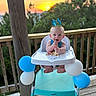 baby, high_chair, balloons, blue, white, crown, cake, crumbs, sunset, outdoor, wooden_deck, happy, smiling, child, person, celebration, birthday, nature, trees, party