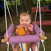 Gia is registered to the contest to win money with this photo: baby_clothing, child, cute, daylight, fence, fun, grass, happy, nature, outdoor, park, picnic_table, playtime, purple_foam, smiling, summer, swing, toddler, toy, tree