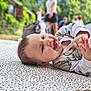 Amalïa participe au concours pour gagner de l'argent avec cette photo : baby, background, blur, casual, cheerful, child, clothing, daylight, face, greenery, hands, happy, infant, lying_down, nature, outdoor, patterned_mat, people, portrait, smiling