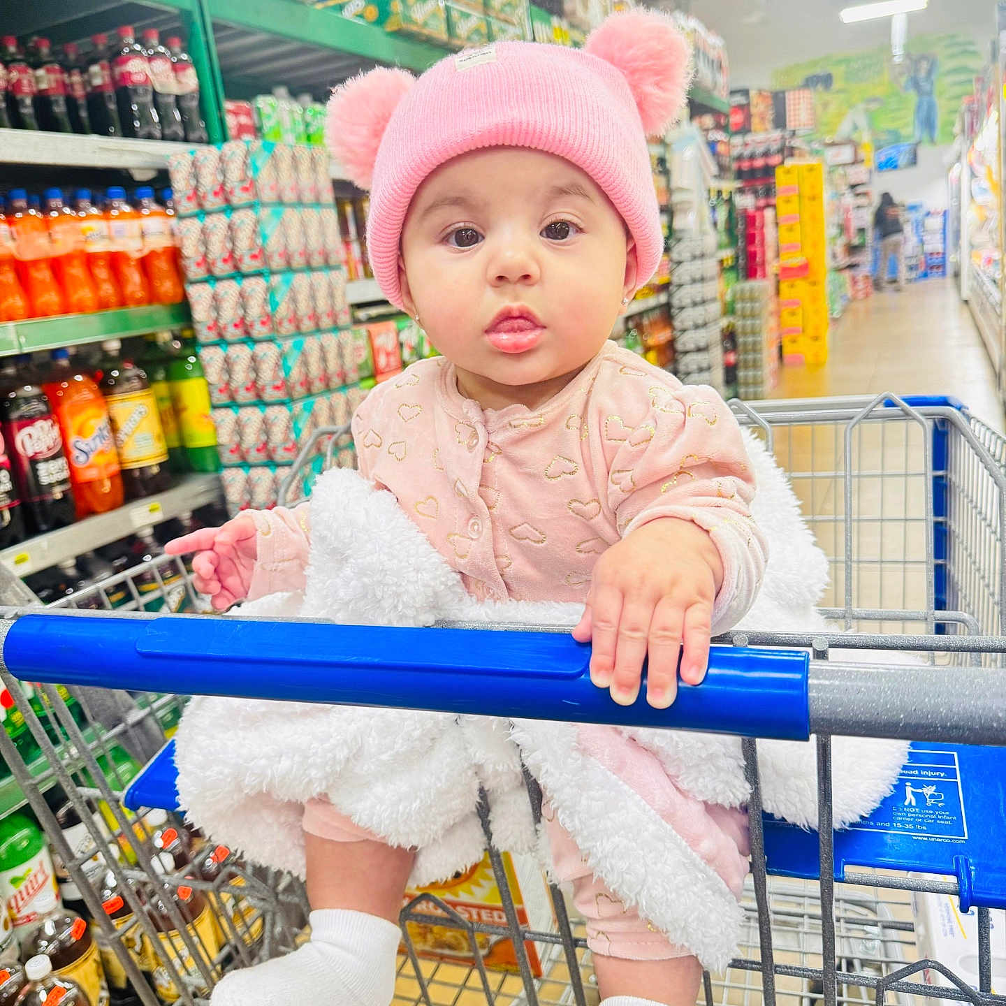 Eimmy joined the competition — help win amazing prizes! baby, beverages, blanket, cart_handle, child, clothing, curious, cute, grocery_store, indoor, infant, person, pink_hat, pom_poms, retail, shelf, shopping, shopping_cart, socks, soda