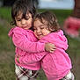 toddler, child, hug, pink_hoodie, plaid_pants, outdoor, grass, happy, joy, affection, cute, smile, clothing, friends, warm_clothes, two_children, playtime, sibling_like, casual_wear, portrait