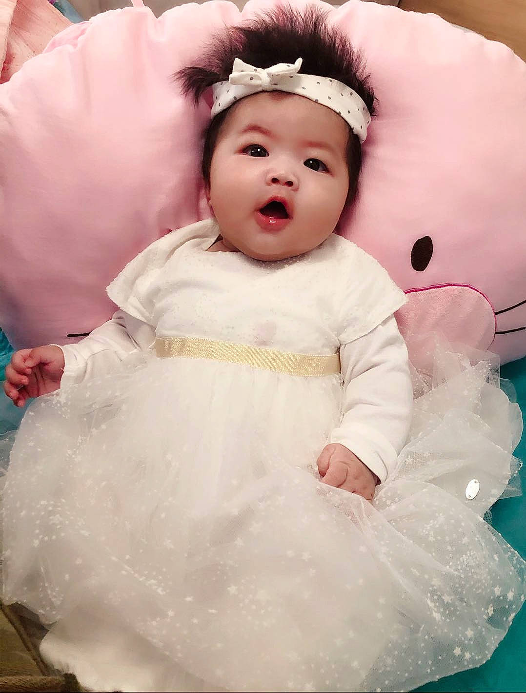 Chloé a rejoint le concours — aidez-le/la à gagner de superbes lots ! baby, cheek, child, costume, dress, face, fur, hair_accessory, happy, head, headwear, person, pink, skin, smile, surprise, toddler, white