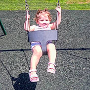 Sadierose is registered to the contest to win money with this photo: chains, child, curly_hair, fence, fun, grass, happy, outdoor, park, play, playground, recreation, sandals, seat, shadow, smiling, summer, sunny, swing, toddler