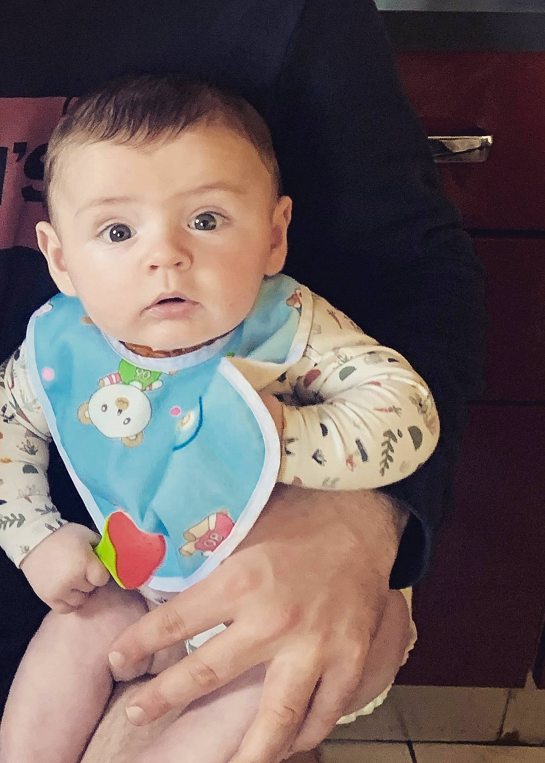 Lino a rejoint le concours — aidez-le/la à gagner de superbes lots ! baby, baby_toddler_clothing, bib, cheek, dress, eye, eyebrow, finger, gesture, hand, happy, iris, lip, nail, neck, nose, person, skin, sleeve, thumb