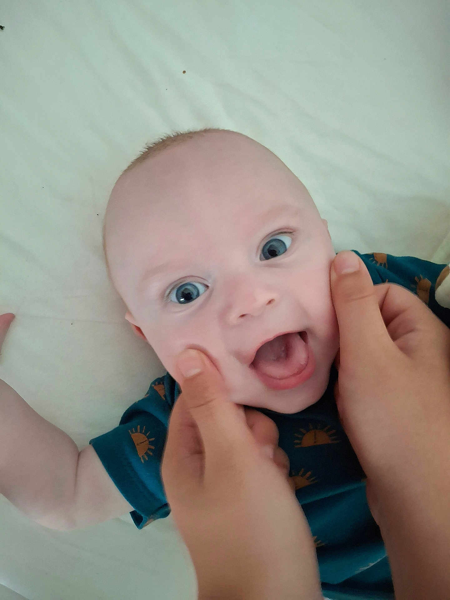 Roman joined the competition — help win amazing prizes! baby, infant, face, hands, blue_eyes, smiling, cheeks, clothing, onesie, person, lying_down, expression, cute, playful, child, skin, mouth_open, human, indoors, white_background