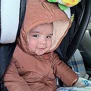 Emiliano joined the competition — help win amazing prizes! baby, child, infant, car_seat, snowsuit, hood, winter_clothing, blanket, bear_pattern, vehicle, portrait, face, smiling, sitting, indoors, cozy, puffy_jacket, car_interior, infant_carrier, cute