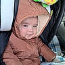 baby, child, infant, car_seat, snowsuit, hood, winter_clothing, blanket, bear_pattern, vehicle, portrait, face, smiling, sitting, indoors, cozy, puffy_jacket, car_interior, infant_carrier, cute