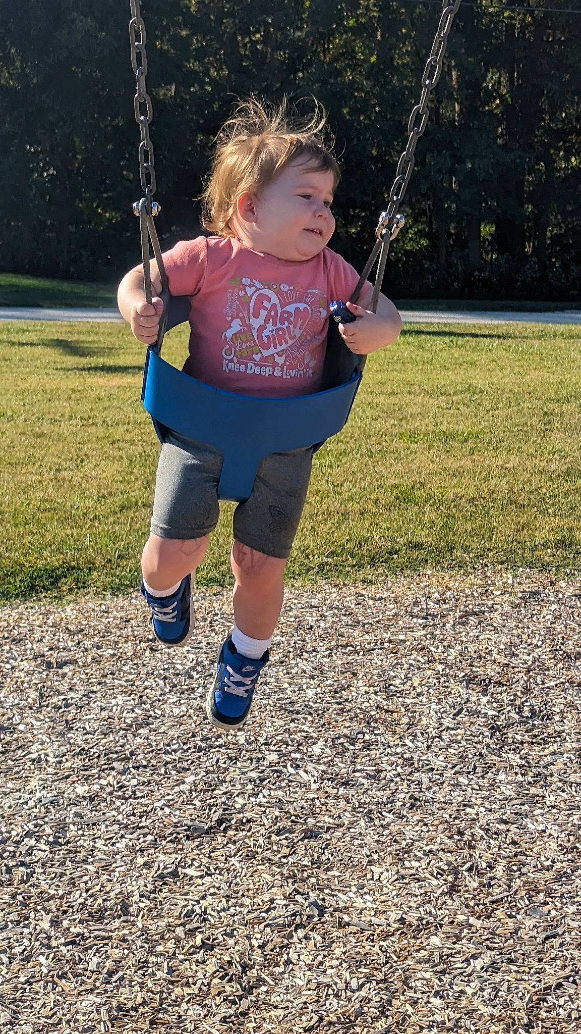 Eliana is registered to the contest to win money with this photo: child, city, electric_blue, fun, grass, happy, human_leg, knee, leisure, outdoor_play_equipment, people_in_nature, person, play, playground, recreation, shorts, sleeve, sock, swing, t_shirt