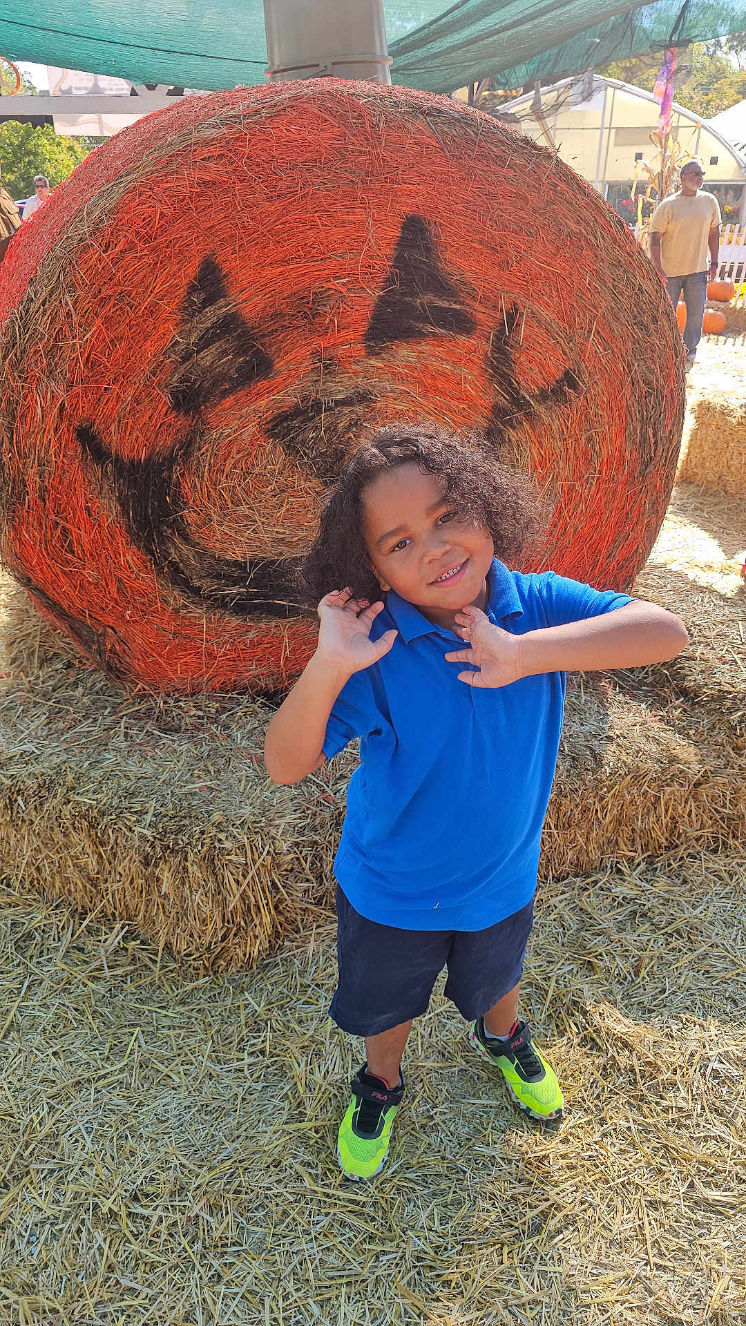Rayden joined the competition — help win amazing prizes! child, boy, smiling, blue_shirt, neon_sneakers, hay_bale, jack_o_lantern, pumpkin_face, autumn, fall_festival, straw, outdoor, playful, curly_hair, festival, decoration, sunny_day, casual_clothing, fun, posing