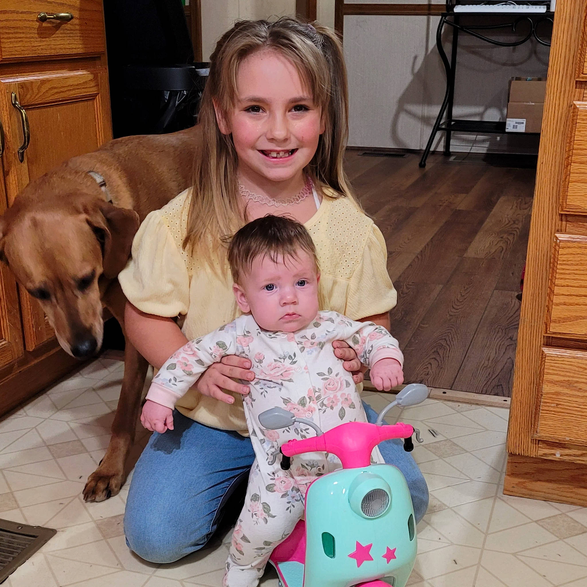 Mallorie is registered to the contest to win money with this photo: baby, baby_toddler_clothing, chair, child, companion_dog, dog, event, flooring, fun, happy, joy, lap, mammal, person, product, room, sitting, skin, smile, toddler