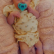Carolynn joined the competition — help win amazing prizes! baby, pacifier, blanket, yellow_clothing, floral_pattern, infant, lying_down, cute, soft_texture, skin, legs, arms, small_hands, portrait, indoors, baby_girl, newborn, comfort, child, resting