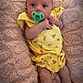 baby, infant, pacifier, yellow_clothing, blanket, pink_blanket, floral_pattern, lying_down, cute, wide_eyes, cozy, soft_texture, small_hands, bare_legs, indoors, portrait, child, newborn, comfort, resting