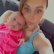 Carolynn is registered to the contest to win money with this photo: baby, blue_eyes, car_interior, casual, child, closeup, clothing, face, holding, human, infant, looking_at_camera, parent, pink_dress, portrait, seat, seatbelt, skin, tank_top, woman