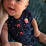 baby, infant, smiling, face, arm, hand, leg, blanket, clothing, polka_dot, navy_blue, pink_bow, strawberry_patch, cute, lying_down, soft_texture, cozy, happy, indoors, child
