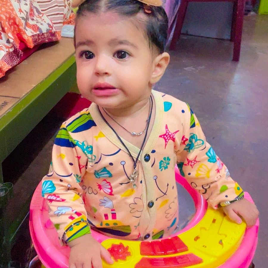 Avitaaz is registered to the contest to win money with this photo: baby, bed, chair, child, clothing, colorful, curious, expression, face, floor, footwear_barefoot, hair_clips, indoors, jumpsuit, person, playful, room, toddler, toy, walker