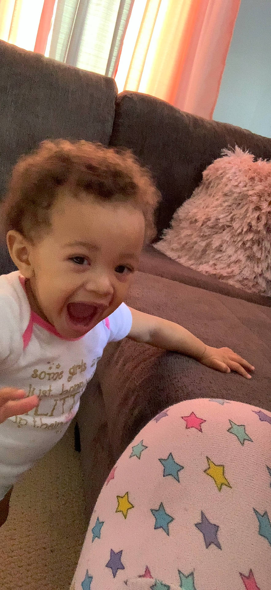 Addie is registered to the contest to win money with this photo: arm, baby_toddler_clothing, beauty, child, comfort, couch, finger, gesture, hairstyle, happy, person, pillow, pink, shoulder, skin, sleeve, smile, t_shirt, thumb, toddler