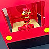 child, firefighter_costume, red_helmet, play_structure, fire_truck, toy, imaginative_play, indoor, wooden_floor, red_color, yellow_detail, steering_wheel, curious, costume, pretend_play, kid, young_child, fun, role_play, bright_colors