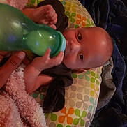 Atlas is registered to the contest to win money with this photo: baby, bottle, hand, blanket, pillow, pattern, colorful, face, infant, feeding, comfort, clothing, person, indoor, soft, sleeping_area, rest, child, young, cute