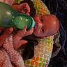 baby, bottle, hand, blanket, pillow, pattern, colorful, face, infant, feeding, comfort, clothing, person, indoor, soft, sleeping_area, rest, child, young, cute