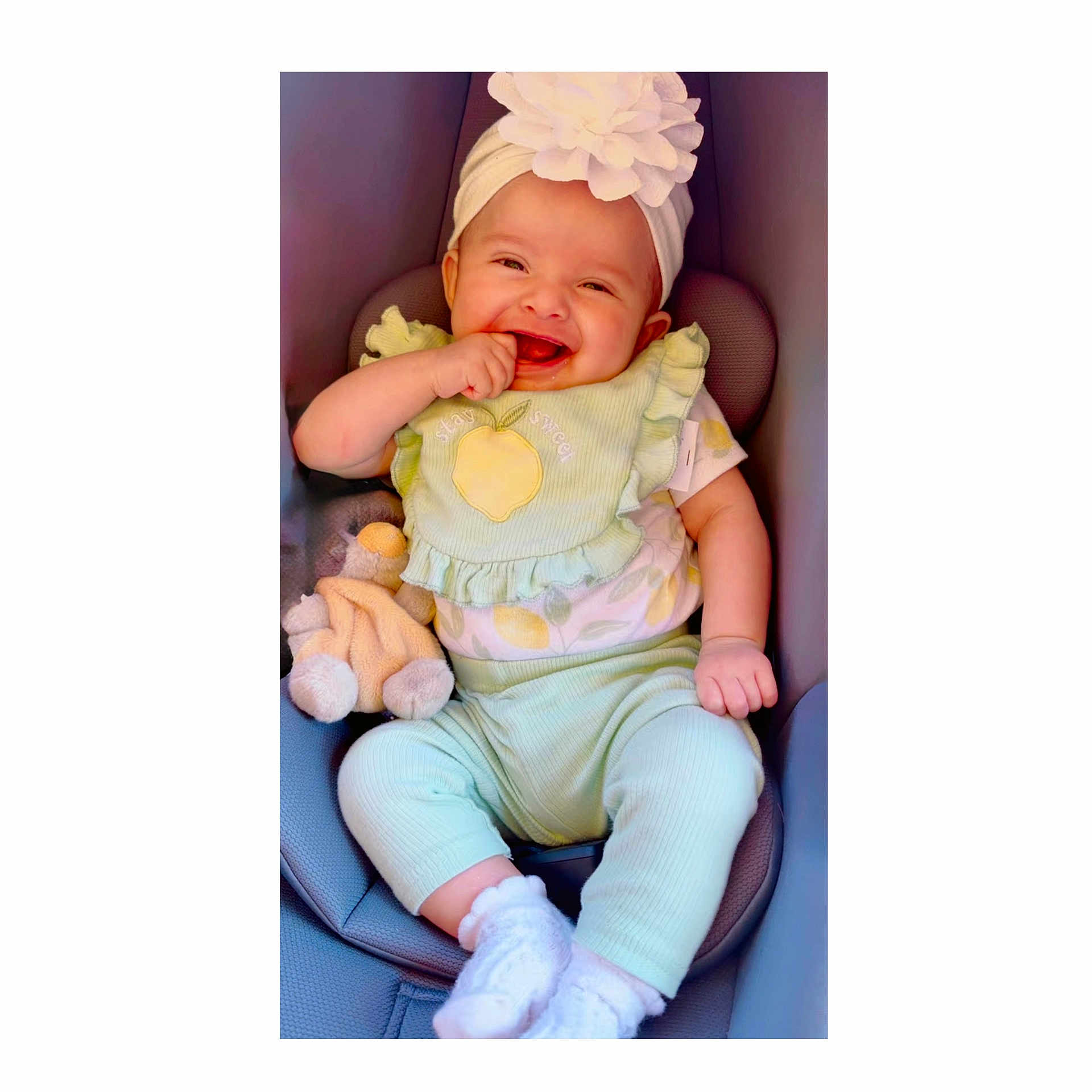 Kaeli is registered to the contest to win money with this photo: baby, child, smiling, happy, portrait, car_seat, headband, flower, plush_toy, infant, sitting, indoors, clothing, pastel_colors, green_outfit, white_socks, finger_in_mouth, joyful, close_up, photography
