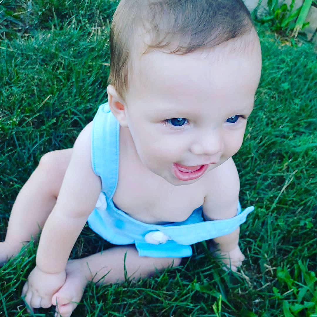 Everest is registered to the contest to win money with this photo: baby_toddler_clothing, cheek, child, electric_blue, eye, fawn, finger, grass, hand, happy, head, iris, joy, lawn, lip, people_in_nature, person, plant, skin, smile