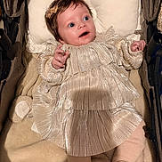 Ambre a rejoint le concours — aidez-le/la à gagner de superbes lots ! baby, infant, stroller, gold_dress, pleated_clothing, blanket, bow, cute, child, portrait, happy, smiling, indoors, soft_texture, clothing, person, baby_girl, head, hands, legs