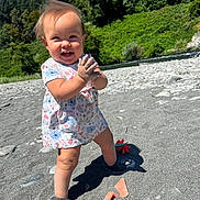 Kalina is registered to the contest to win money with this photo: toddler, child, smiling, outdoor, beach, sand, rocks, toys, dress, shoes, sunny, nature, trees, river, clapping, happy, daytime, play, baby, person