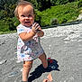 toddler, child, smiling, outdoor, beach, sand, rocks, toys, dress, shoes, sunny, nature, trees, river, clapping, happy, daytime, play, baby, person