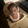baby_food, carpet, child, curiosity, curly_hair, cute, expression, face_paint, feeding, food, furniture, high_chair, indoor, messy, plate, portrait, spoon, table, toddler, white_tank_top