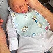 Ronnie is registered to the contest to win money with this photo: newborn, baby, infant, sleeping, hands, onesie, bib, animal_prints, white_clothing, gentle_touch, tenderness, resting, closeup, indoor, soft_light, family, care, comfort, peaceful, portrait