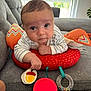 baby, infant, couch, red_cushion, toy, striped_clothing, indoor, living_room, face, head, hand, curious, expression, window, blinds, soft_toy, colorful, person, close_up, comfortable