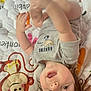 toddler, child, baby, upside_down, quilt, cartoon, monkey, gray_shirt, sloth, clothing, smiling, playful, hands, feet, hair, face, indoor, blanket, cute, happy