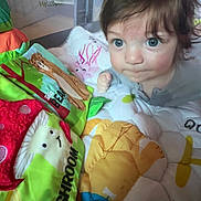 Wesley is registered to the contest to win money with this photo: baby, child, indoor, playpen, quilt, colorful, toy, animal_design, mushroom, face, blue_eyes, curious, tousled_hair, closeup, soft_lighting, infant, cute, expression, bedroom, fabric