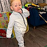 toddler, child, indoor, tracksuit, sneakers, floor, playful, toys, curtain, sofa, clothing, person, young_child, home, carpet, furniture, smile, standing, hair, expression