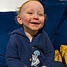 Beau joined the competition — help win amazing prizes! toddler, child, smiling, blue_sweater, couch, indoor, happy, face, person, cozy, blanket, seated, young_child, casual_clothing, rosy_cheeks, small_object, home, portrait, cute, warm_lighting