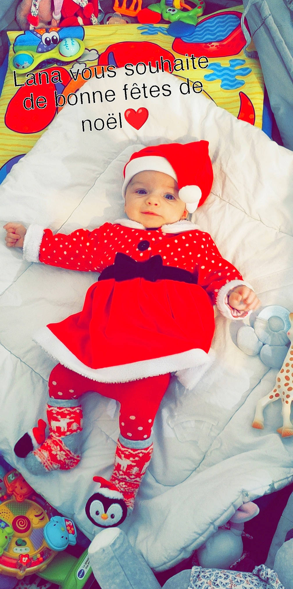 Lana participe au concours pour gagner de l'argent avec cette photo : baby, baby_products, baby_toddler_clothing, child, christmas, event, face, fictional_character, happy, hat, headwear, holiday, pattern, person, pink, product, red, skin, sleeve, textile