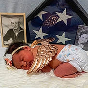 Esmae is registered to the contest to win money with this photo: newborn, baby, angel_wings, headband, flower, diaper, sleeping, blanket, fluffy, portrait, indoor, photography, memorial, flag, framed_photos, black_and_white, family, tribute, soft_lighting, peaceful